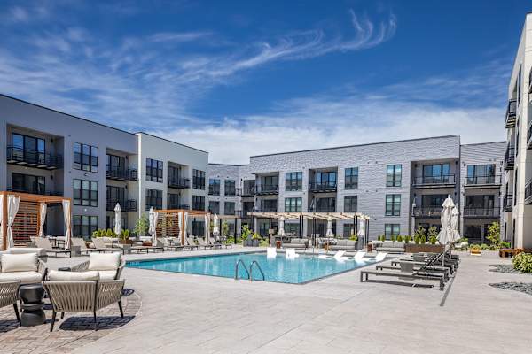 A large swimming pool surrounded by lounge chairs and umbrellas at The Plaza at Pinnacle Hills in Rogers, AR.
